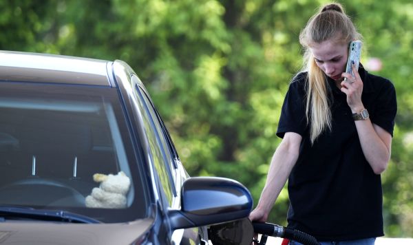 Женщина заправляет автомобиль на автозаправочной станции 