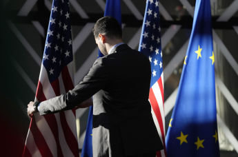 Рабочий поправляет флаги США и ЕС