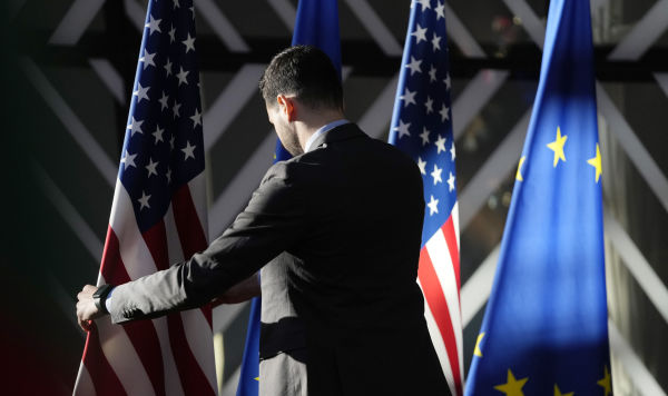 Рабочий поправляет флаги США и ЕС