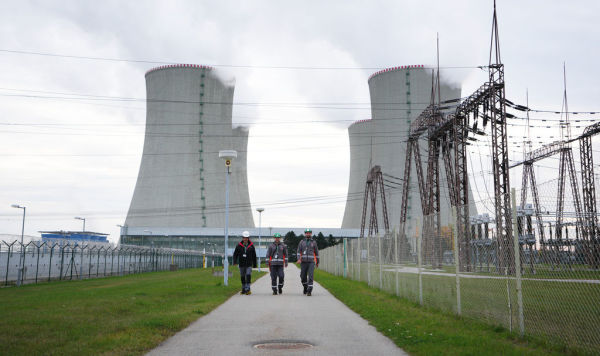 Рабочие проходят мимо градирен атомной электростанции Дукованы, Чехия, 21 октября 2025 года