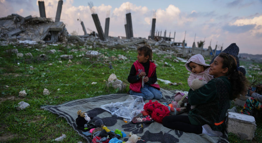 Семья на фоне разрушенных зданий в Нусейрате, центр сектора Газа