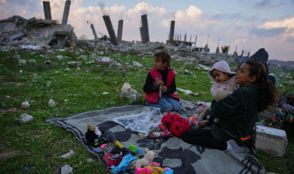 Семья на фоне разрушенных зданий в Нусейрате, центр сектора Газа