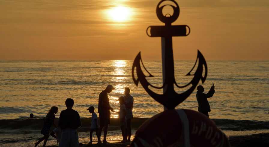 Российские отдыхающие наблюдают закат на берегу моря в Янтарном