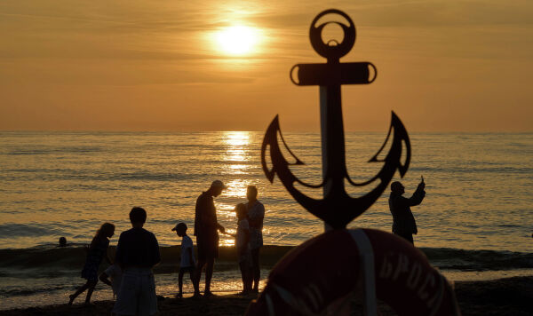 Российские отдыхающие наблюдают закат на берегу моря в Янтарном