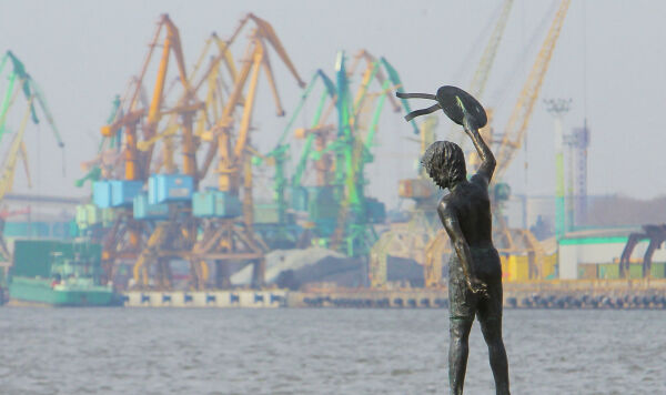 Памятник мальчику с бескозыркой и собакой, который провожает корабли в морском грузовом порту Клайпеды