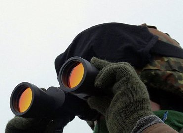 Военный смотрит в бинокль.
